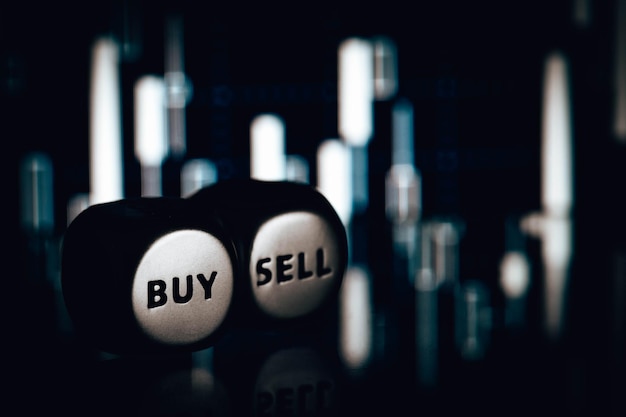 Photo sell and buy dice on blurred candlestick chart closeup stock photo