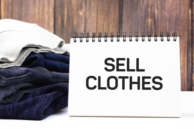 SELL CLOTHES text on a notepad next to clothes