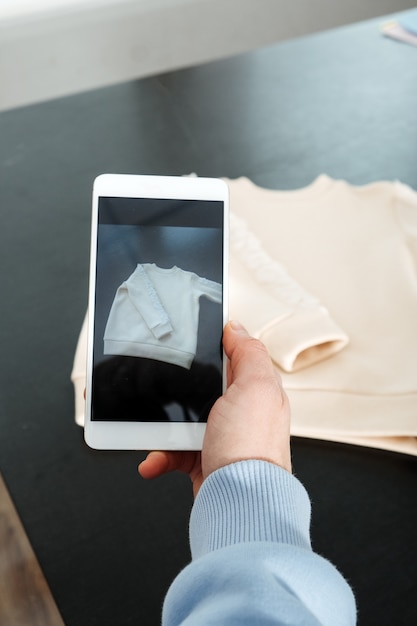 Photo sell online on the internet ecommerce store woman taking photo of clothes on smartphone selling