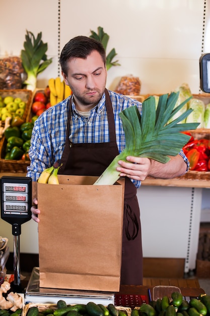 Seller in apron puts purchases in a package.