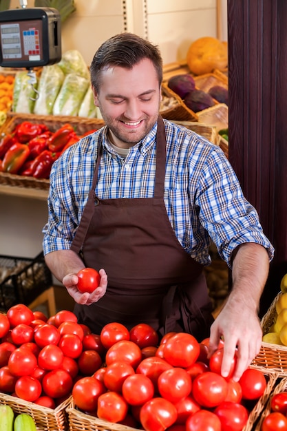 Seller in apron sorts tomatoes.