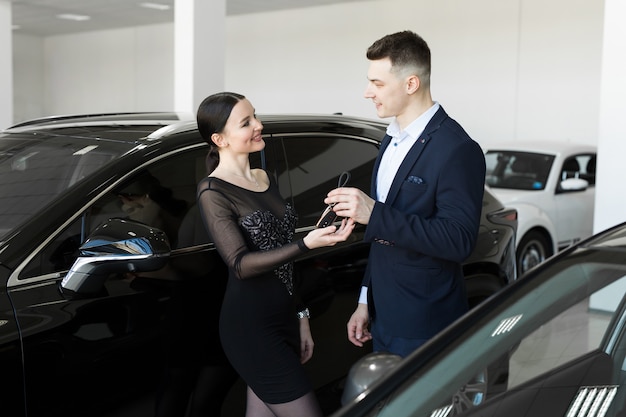 Seller gives the buyer the keys to a new car in the showroom