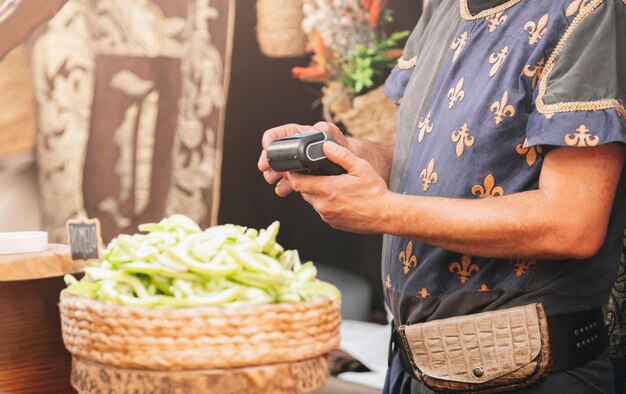 Photo seller holding dataphone in medieval steet market in medieval clothes