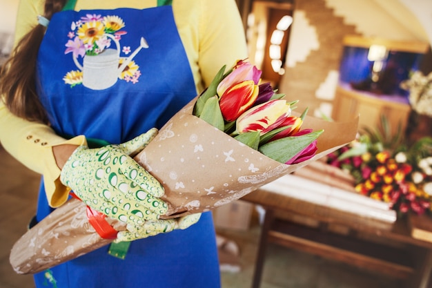 The seller holds a large beautiful bouquet of tulips packed in craft paper, side view