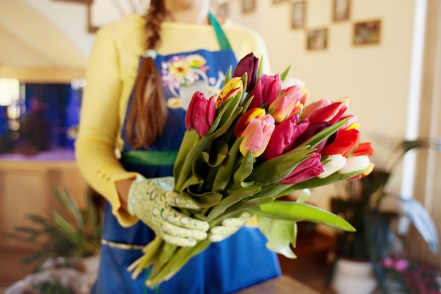 The seller holds a large beautiful bouquet of tulips packed. Side wiev