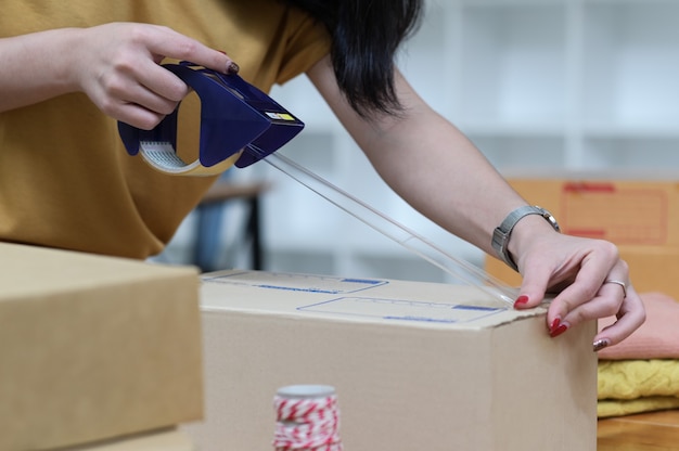 The seller is packing boxes to prepare for shipping.