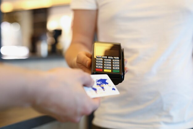 판매자 남자는 고객에게 신용 카드로 터미널을 통해 온라인으로 지불하도록 제안합니다.