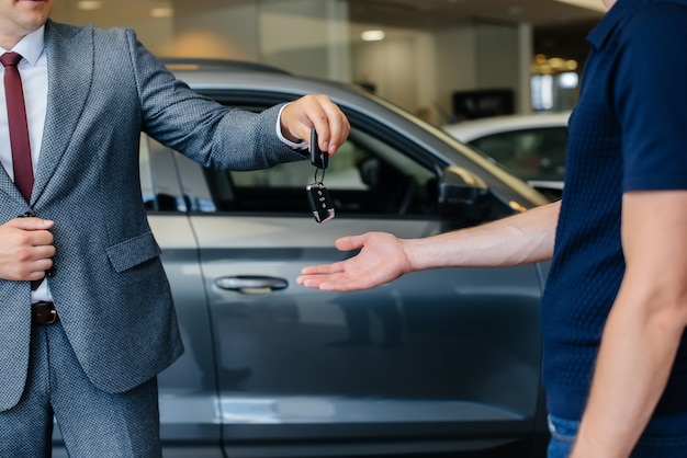 The seller passes the keys to a new car to a young family. Buying a new car.