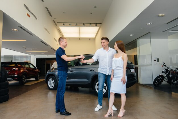 The seller passes the keys to a new car to a young family