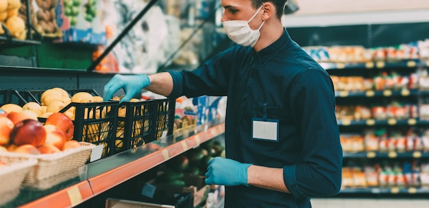 Seller in a protective mask standing in front of the counter with fruit. coronavirus in the city