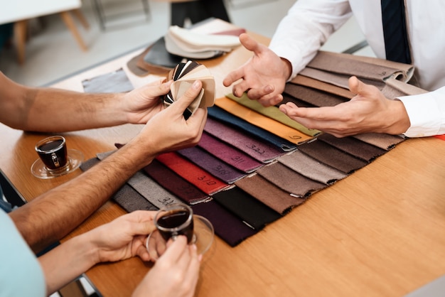 The seller shows samples of materials for furniture.