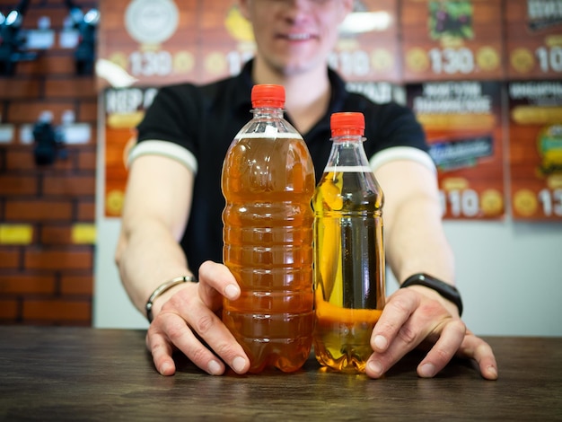 The seller in the supermarket holds a beer in his hands