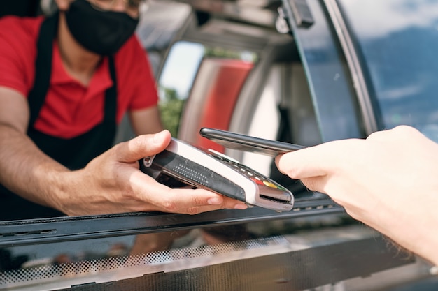 Seller of takeout food holding payment terminal while client paying for snack