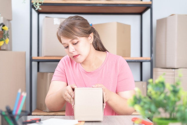 집에서 온라인 작업 판매 포장 상자를 들고 집에서 일하는 여성 사업주
