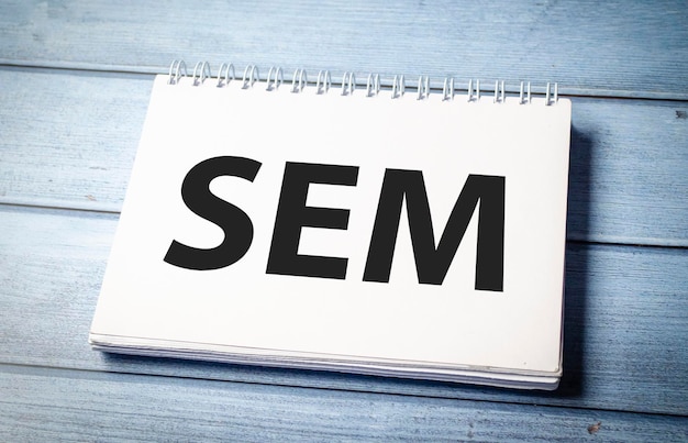 検索エンジンマーケティング (SEM) はホワイトテーブルの上に書かれたノートブックです