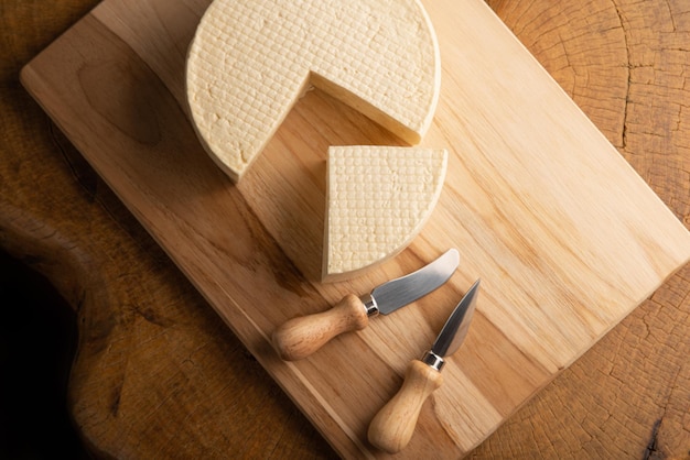 Semi-cured cheese from Brazil, beautiful Brazilian cheeses and cutting accessories arranged on light rustic wood, selective focus.