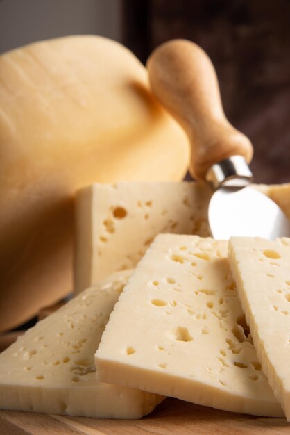 Semi-cured cheese from brazil, beautiful brazilian cheeses and\
cutting accessories arranged on light rustic wood, selective\
focus.