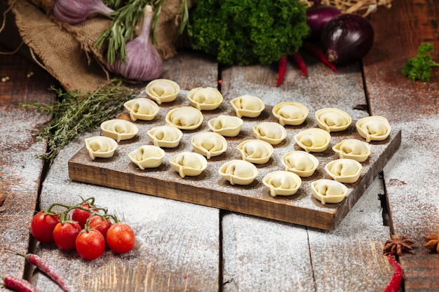 Semi-finished pelmeni dumplings on wooden board