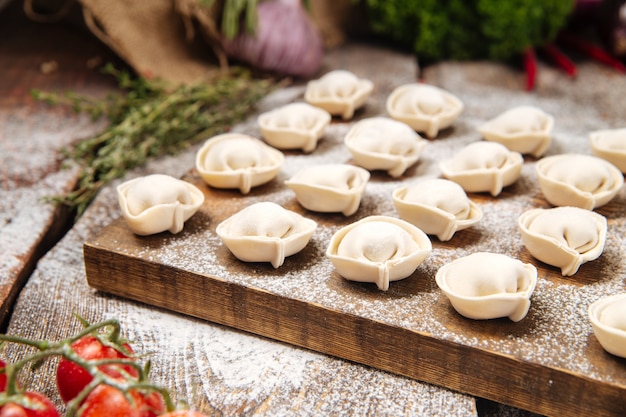 Semi-finished pelmeni dumplings on wooden board