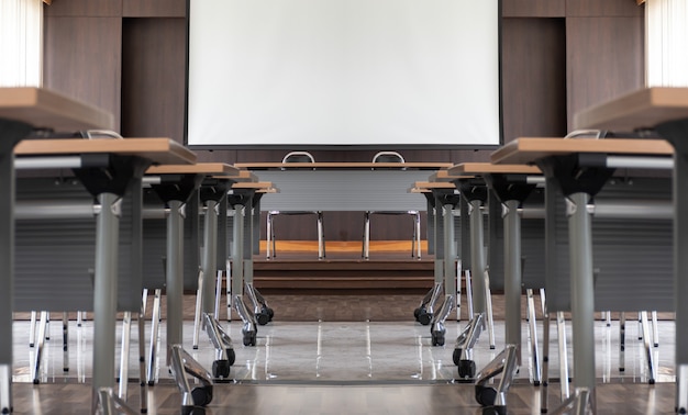 Seminar room with a speaker table on stage and whitescreen background