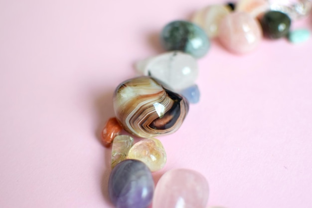 Semiprecious stones of different colors on a pink background. Selective focus