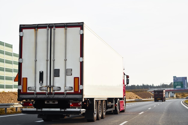 Semitrailer trucks transporting cargo on the highway The trucks are delivering goods by land from door to door They are part of a global sustainable logistics industry that supports trade commerce