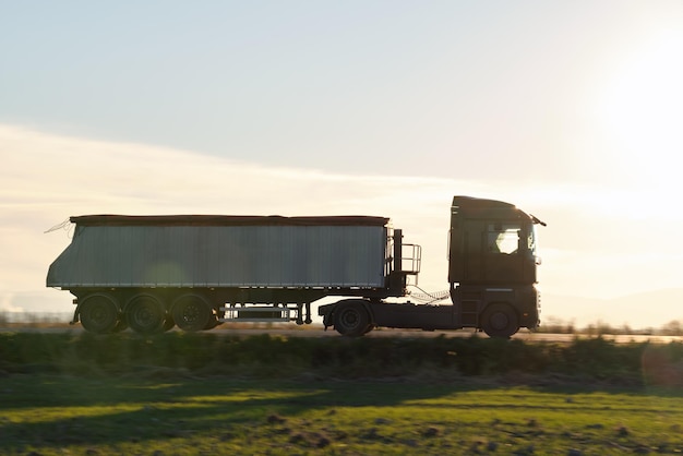 Foto semitruck met kiepvrachtaanhangwagen die zand vervoert uit steengroeve die op de snelweg rijdt en goederen 's avonds vervoert leveringstransport en logistiek concept