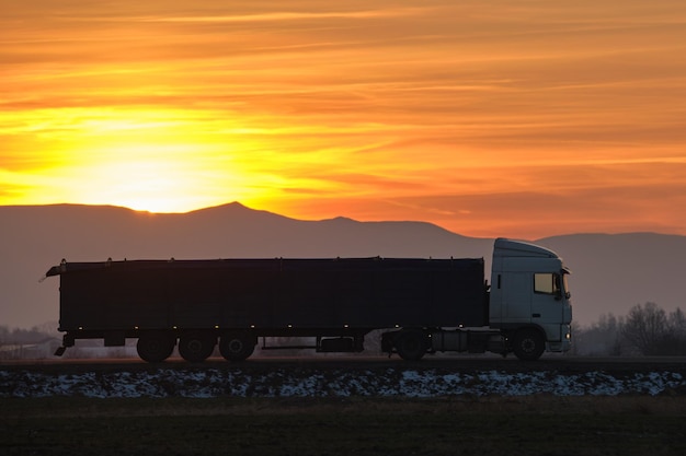 Semitruck met vrachtaanhangwagen die 's avonds op de snelweg rijdt en goederen vervoert Leveringstransport en logistiek concept