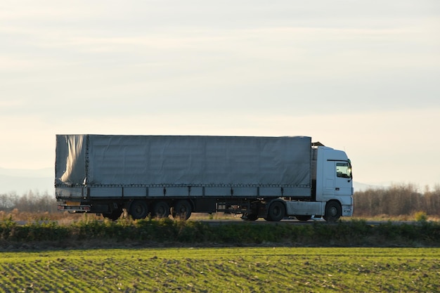 Semitruck met vrachtaanhangwagen die 's avonds op de snelweg rijdt en goederen vervoert leveringstransport en logistiek concept