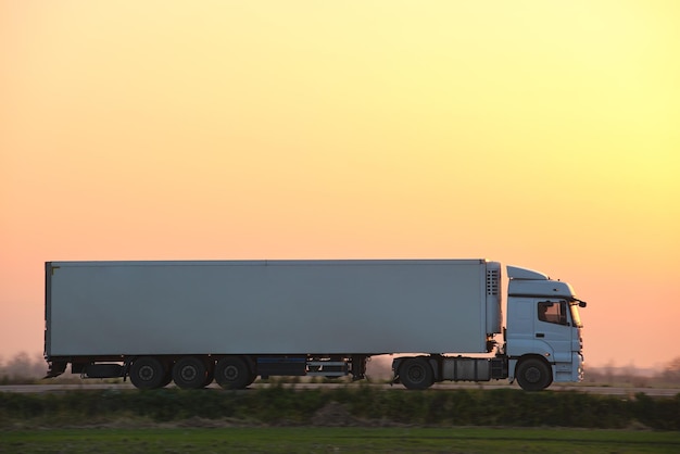 Semitruck with cargo trailer driving on highway hauling goods in evening Delivery transportation and logistics concept