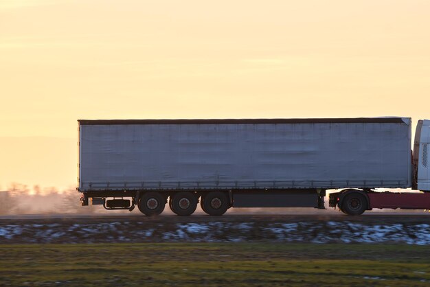 Semitruck with cargo trailer driving on highway hauling goods in evening Delivery transportation and logistics concept