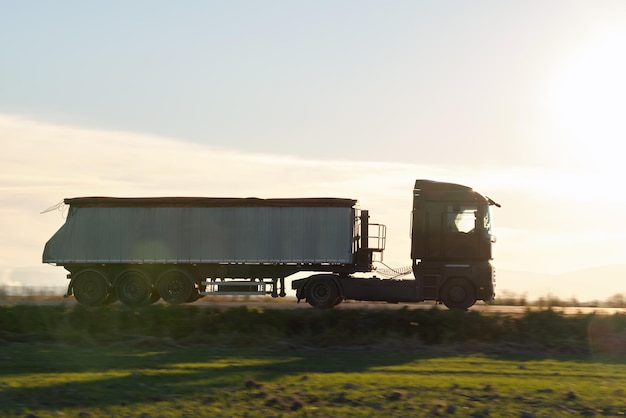 Photo semitruck with tipping cargo trailer transporting sand from quarry driving on highway hauling goods in evening delivery transportation and logistics concept