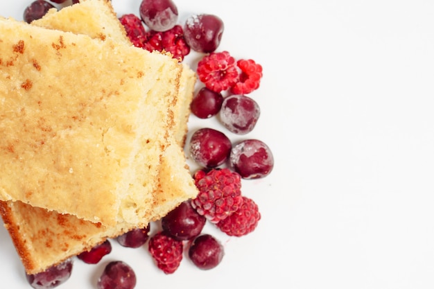 Semolina cake with raspberries and cherries isolated on white surface