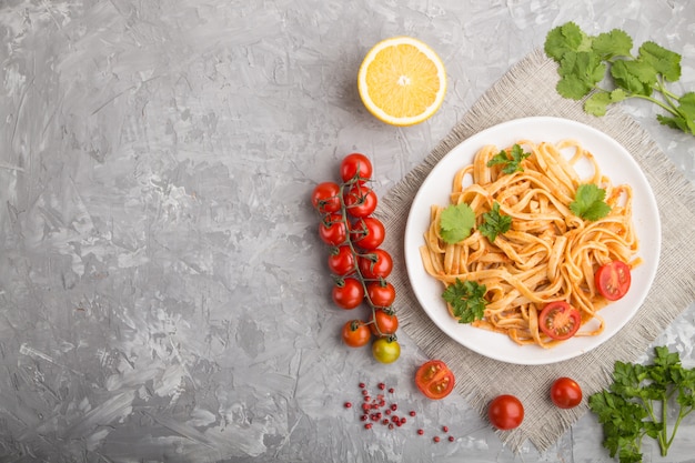 Semolina pasta with tomato pesto sauce, orange and herbs. Top view, copyspace.