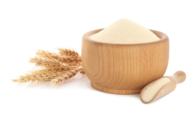 Semolina in wooden bowl and scoop on white background