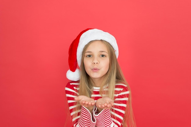 Send kisses christmas party cheerful girl having fun christmas eve joyful kid child santa costume believe in miracle girl little kid on red background merry christmas and happy new year