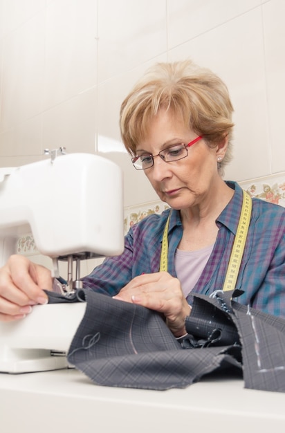 Senion seamstress woman working on sewing machine