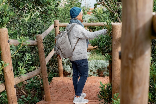 Senior active caucasian woman on hiking trip with backpack enjoying freedom and nature