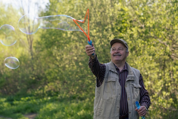 Senior active man plays with soap bubbles outdoor