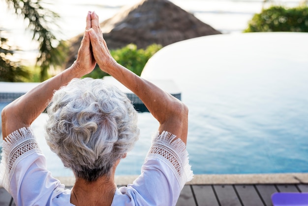 Senior adult practicing yoga by the pool