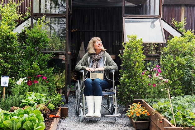 Donna adulta senior sulla sedia a rotelle nel giardino