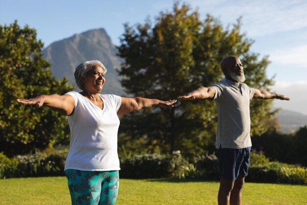Photo senior african american couple practicing yoga in stunning countryside retreat. retirement and active senior lifestyle concept.