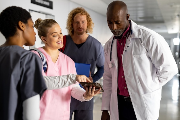 Senior african american male doctor talking to diverse trainee doctors in corridor at hospital