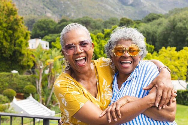 Senior African American woman and senior biracial woman share a joyful embrace outdoors