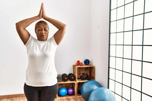 Senior african american woman training yoga at sport center