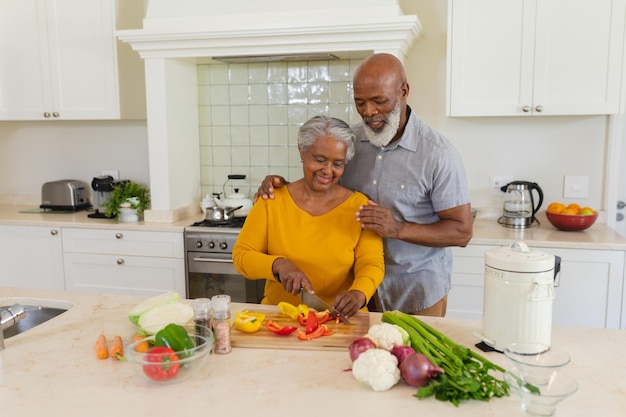 Senior Afrikaans Amerikaans echtpaar kookt samen in de keuken glimlachend. retraite, pensioen en gelukkig senior levensstijlconcept.