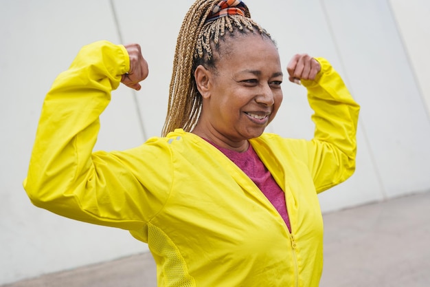 Senior afrikaanse vrouw die biceps spier toont tijdens sporttraining in de stad