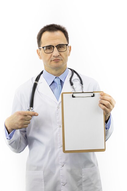 Senior age doctor in medical coat pointing on clipboard with blank paper