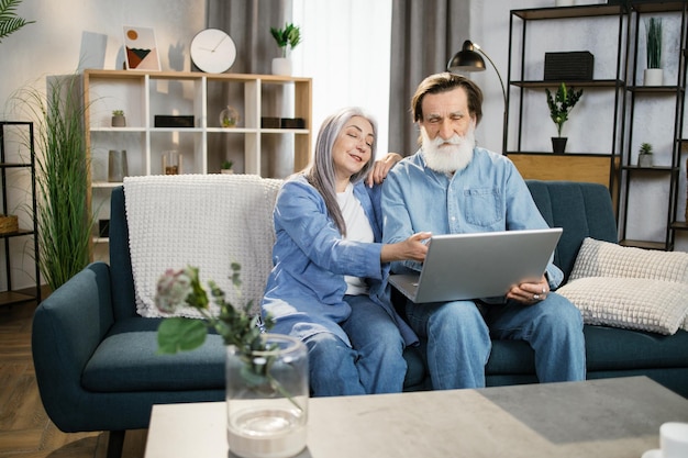 Senior aged happy couple embracing using laptop together