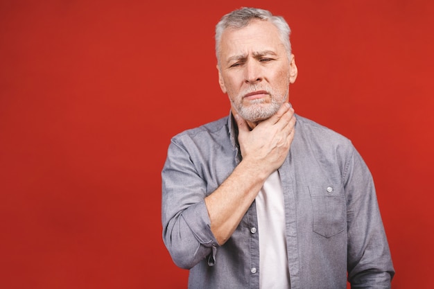 Senior aged man having sore throat and touching his neck, wearing a casual clothing isolated. Hard to swallow.